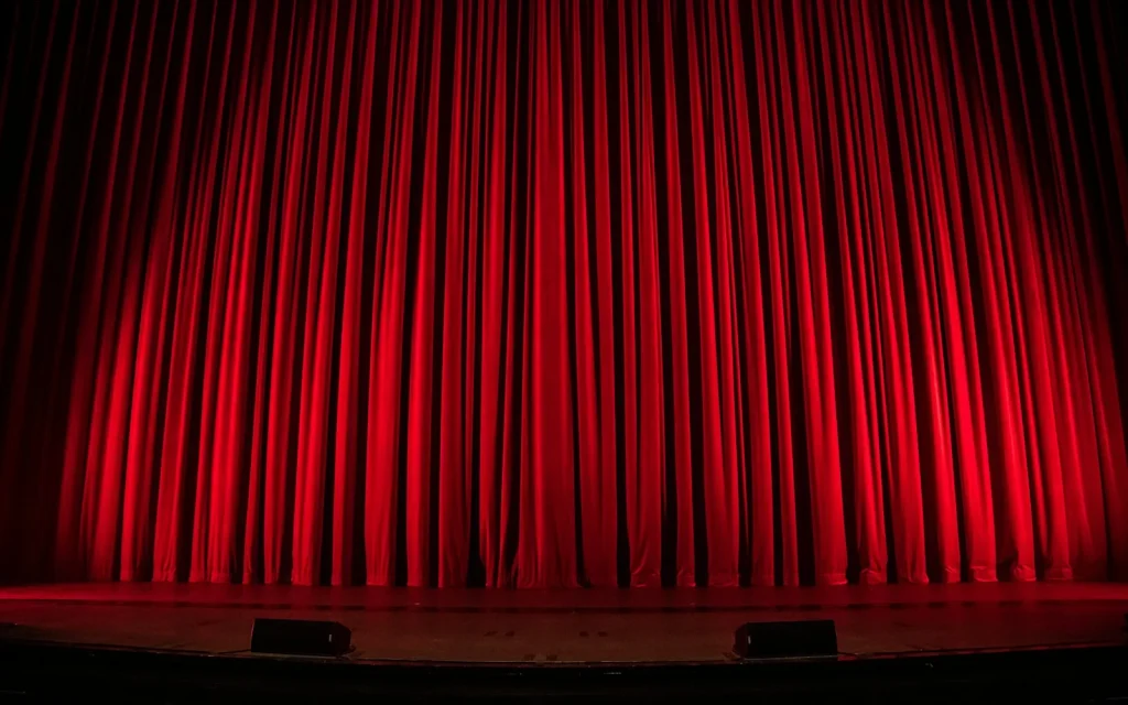 Rideau de scène rouge dramatique éclairé, théâtre immersif